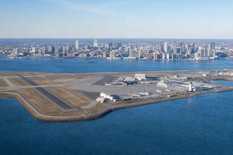 Aircraft at a Logan International Airport terminal with the Boston skyline across the harbor
