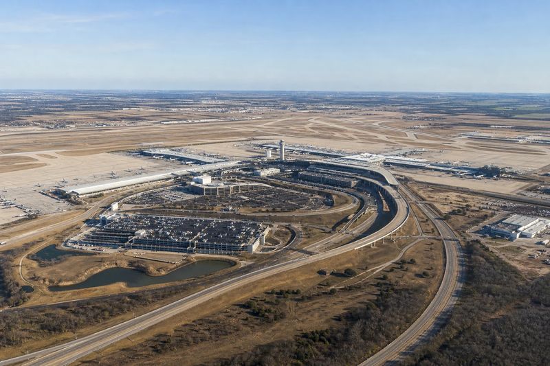 A curved terminal building with aircraft at its gates at Dallas/Fort Worth International Airport
