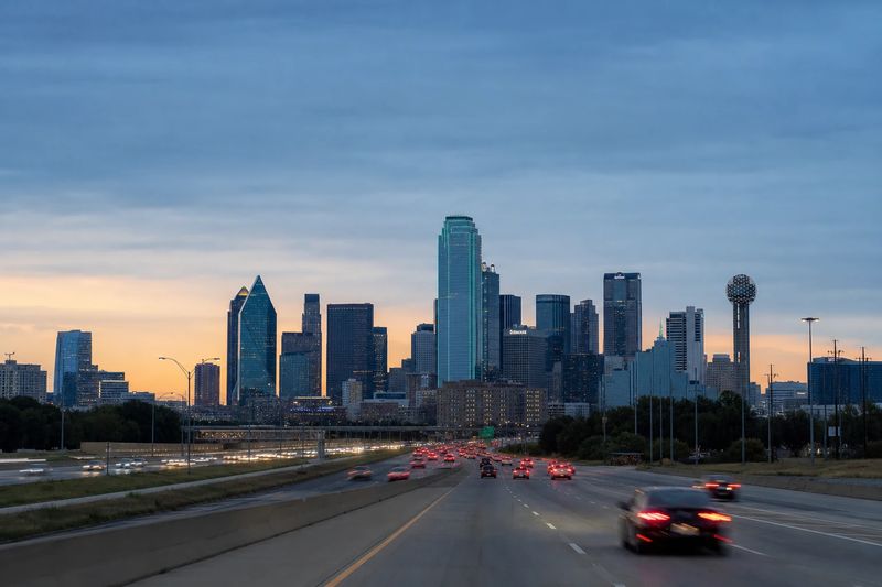 The downtown Dallas skyline at dusk seen from across a wide freeway interchange