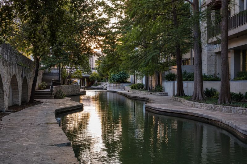 The San Antonio River Walk below street level in downtown, with stone footbridges crossing the water